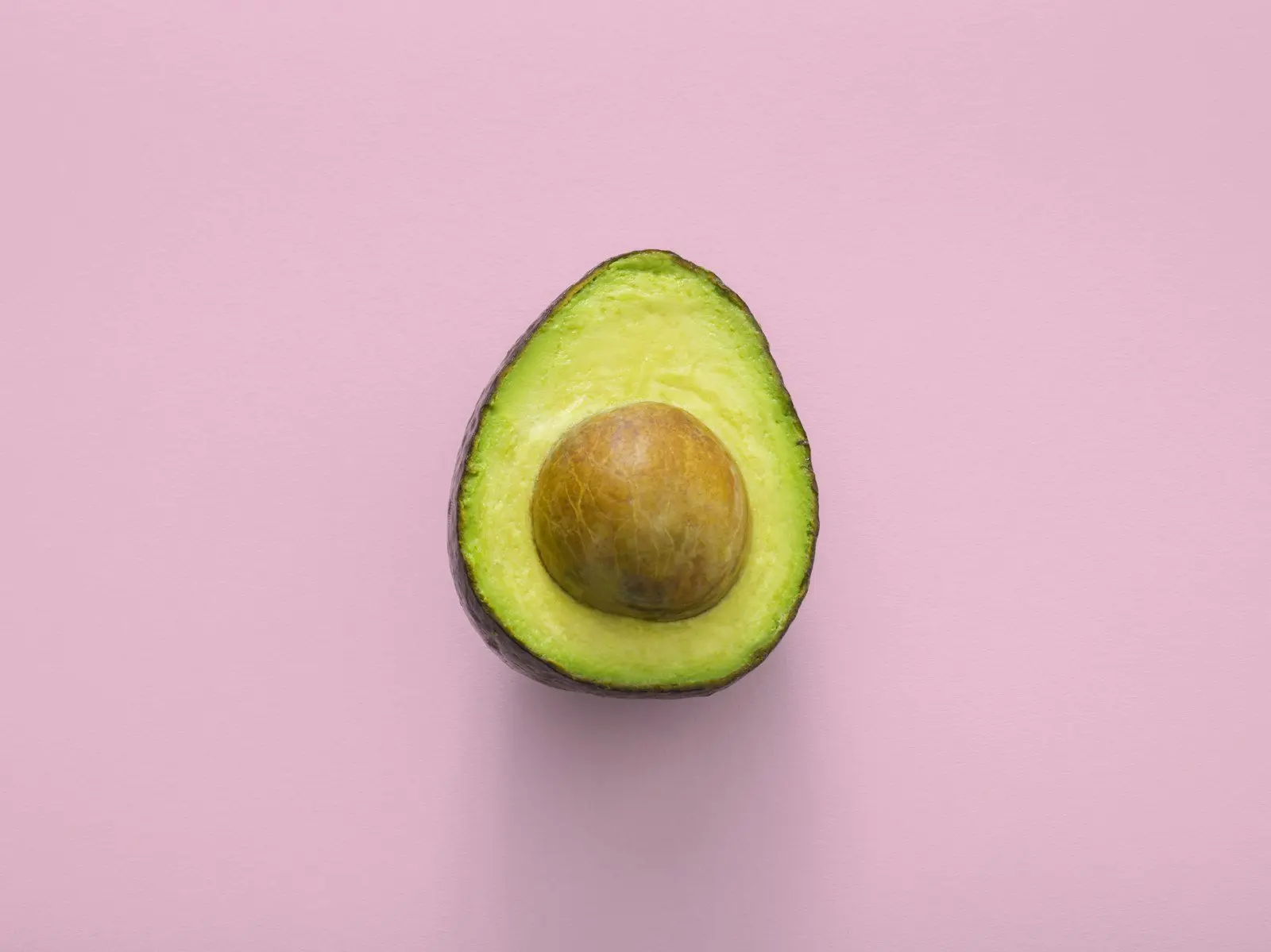 A halved avocado showing pale green flesh around the stone