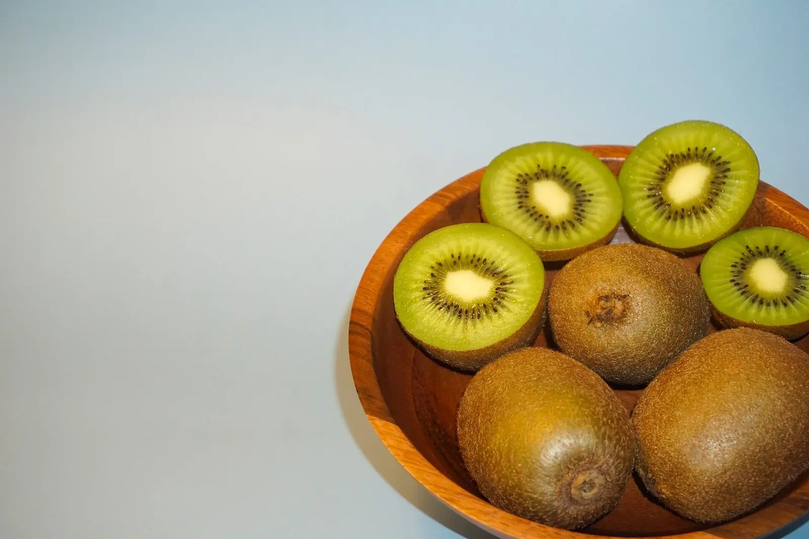 Kiwifruit cut in half beside whole fruit, showing the green flesh and black seeds